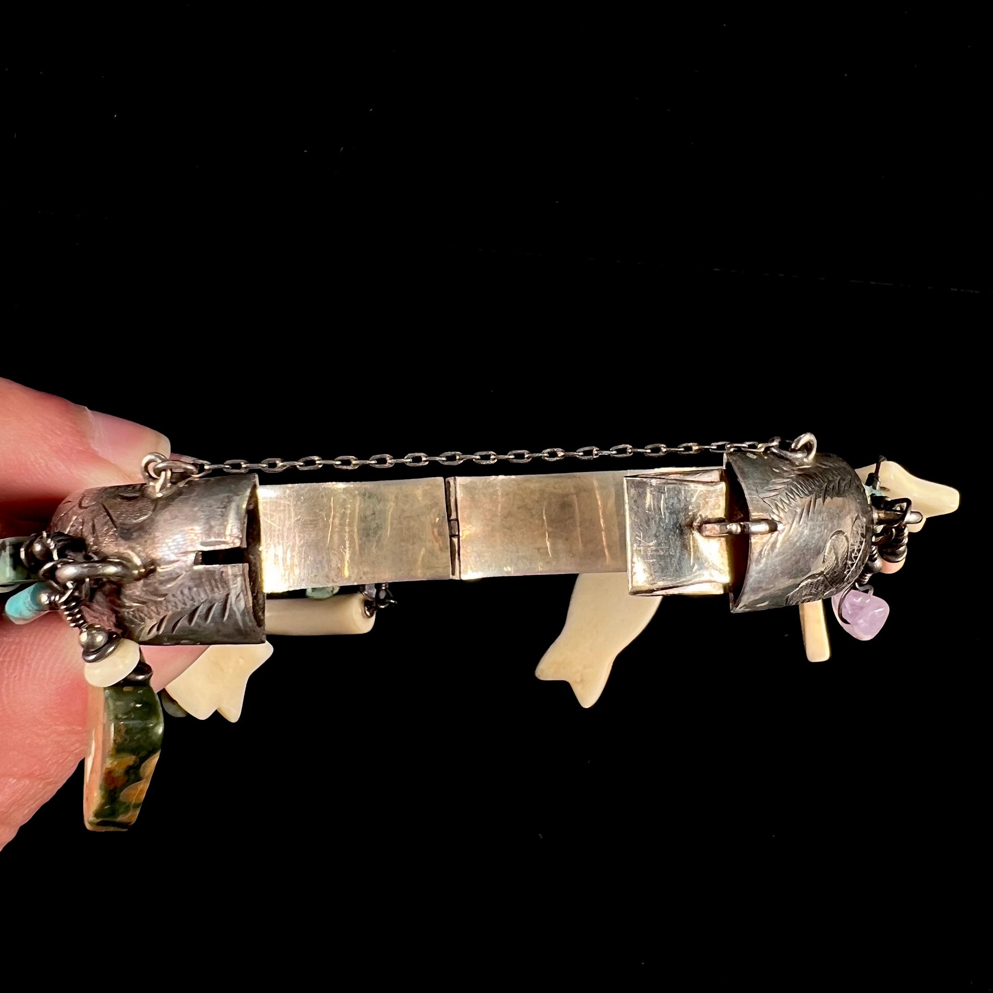 A Native American sterling silver bangle bracelets attached with carved bone, gemstone, and silver charm fetishes.