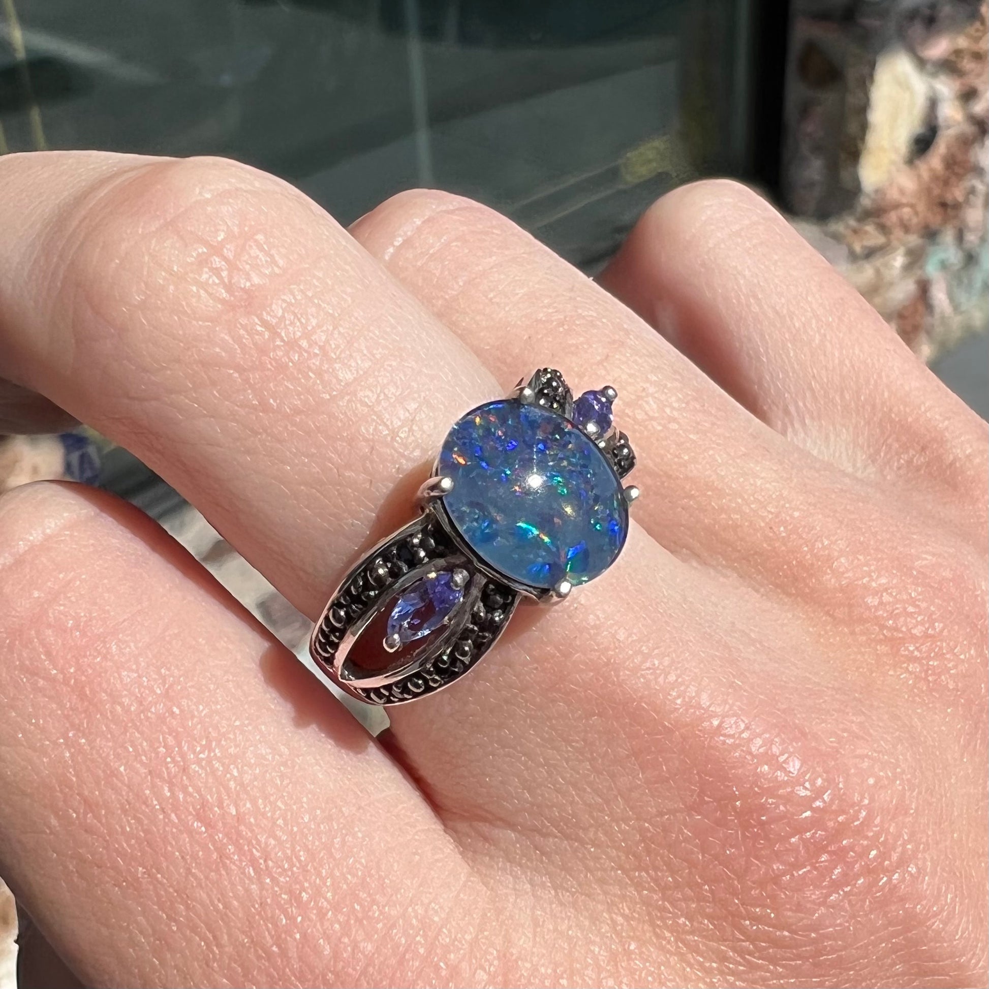 A sterling silver black opal triplet ring set with black spinel and marquise cut tanzanite accent stones.
