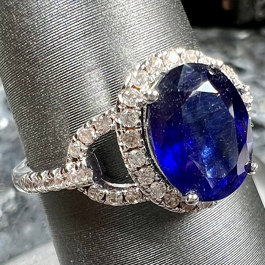 A sterling silver, white zircon halo ring set with an oval cut blue sapphire.