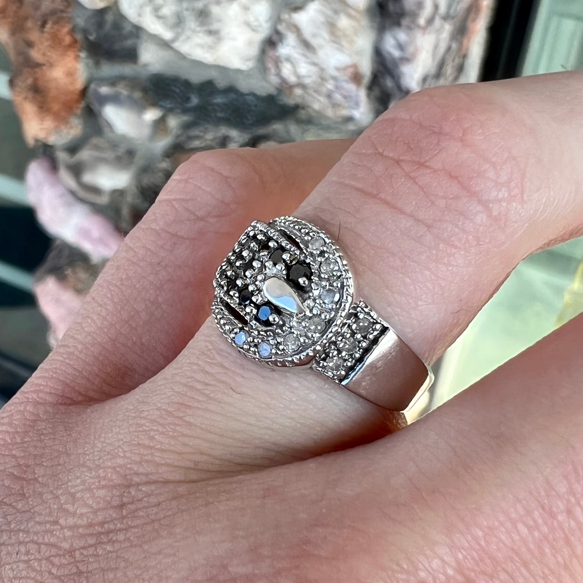 A white gold buckle ring pave set with round black and white diamonds.