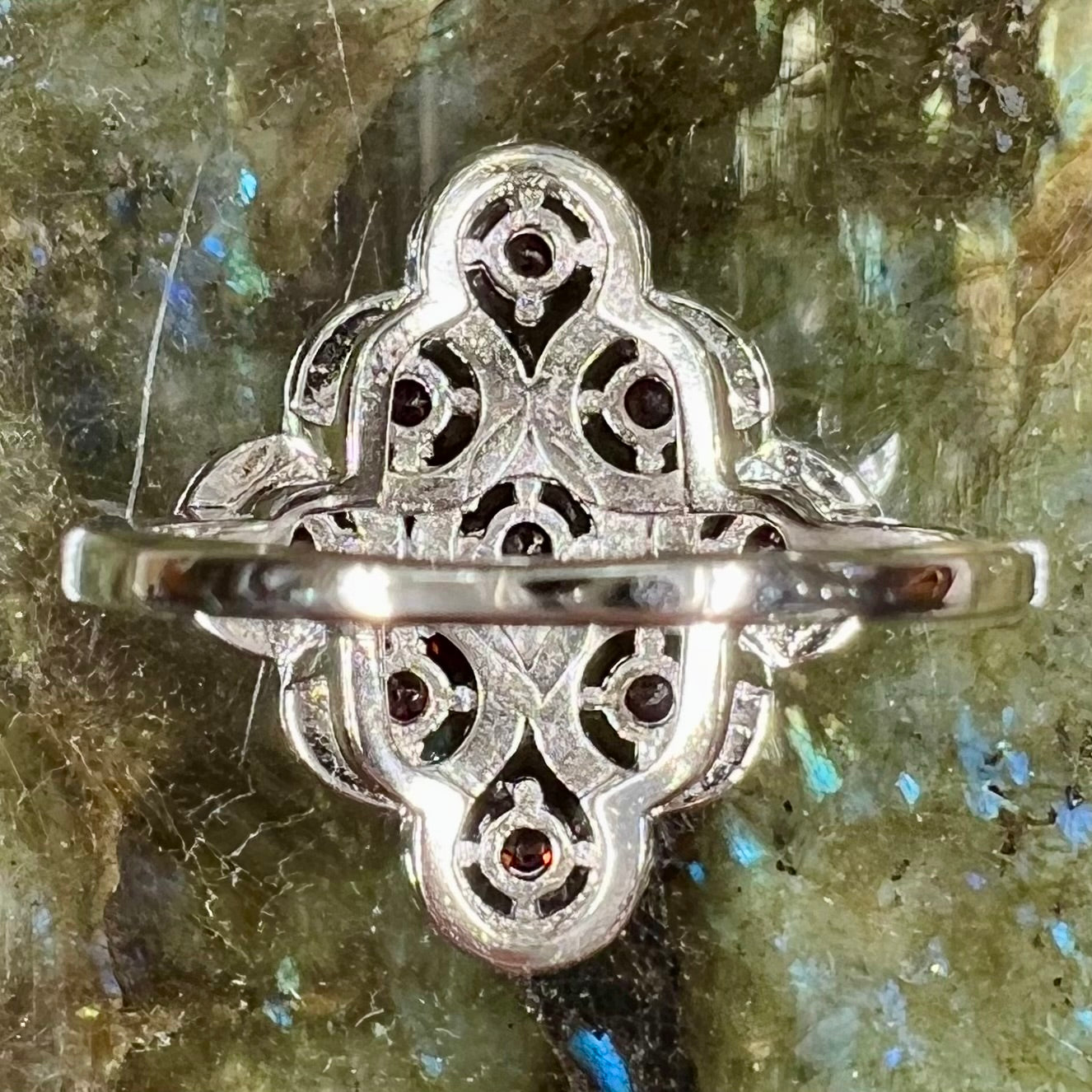 A sterling silver cluster ring set with round almandine garnet main stones and white zircon accents.