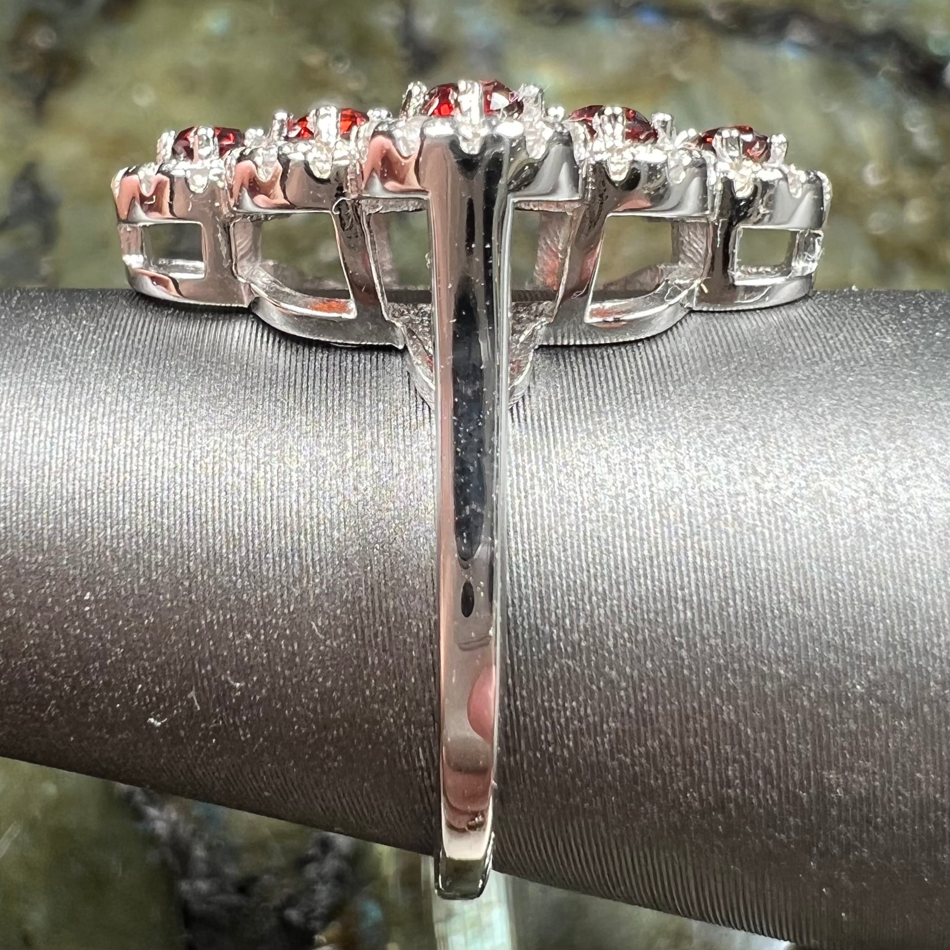 A sterling silver cluster ring set with round almandine garnet main stones and white zircon accents.