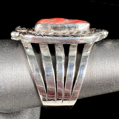 A sterling silver ring set with a polished red coral branch handmade by Navajo artist, Delbert Chatter.