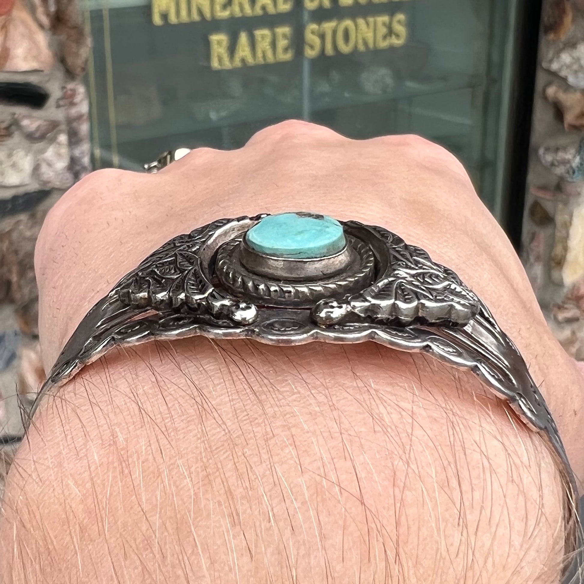A base metal cuff bracelet set with a round cabochon cut imitation blue turquoise stone.