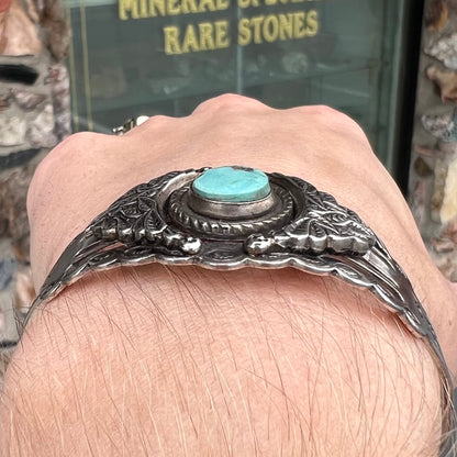 A base metal cuff bracelet set with a round cabochon cut imitation blue turquoise stone.