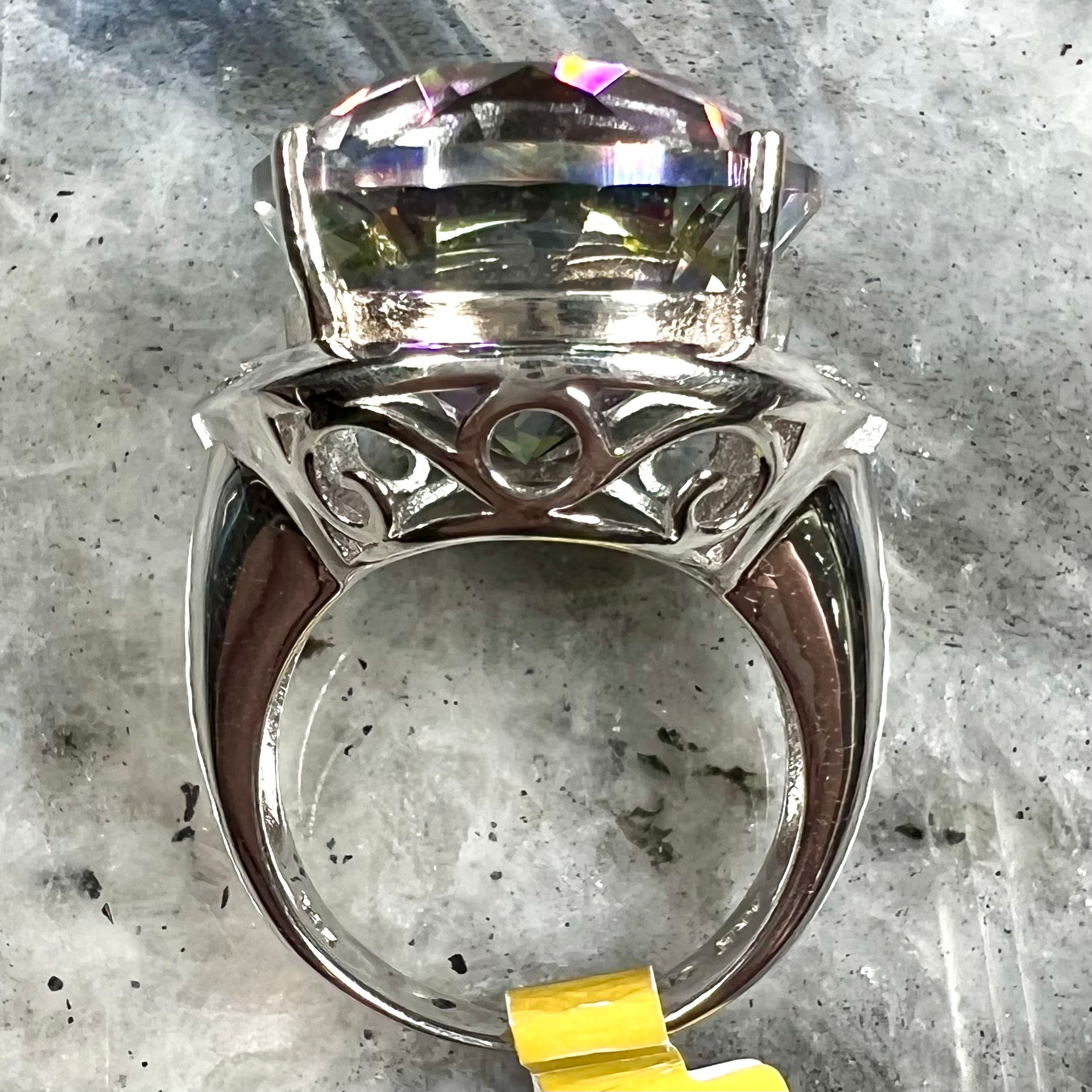 A large, round cut pink and green mystic topaz set in a sterling silver ring with white topaz accent stones.