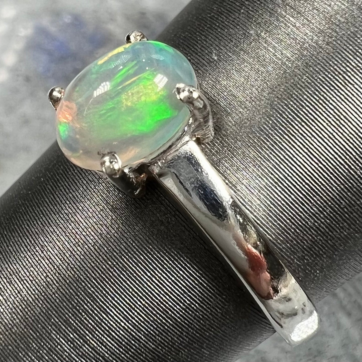 A silver, prong set, oval cabochon cut Ethiopian opal solitaire ring.