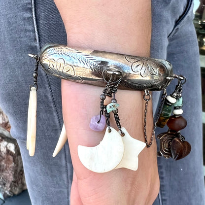 A Native American sterling silver bangle bracelets attached with carved bone, gemstone, and silver charm fetishes.
