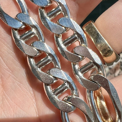 A men's sterling silver figaro anchor chain.  The chain measures 22 inches in length and the links are 11mm wide.