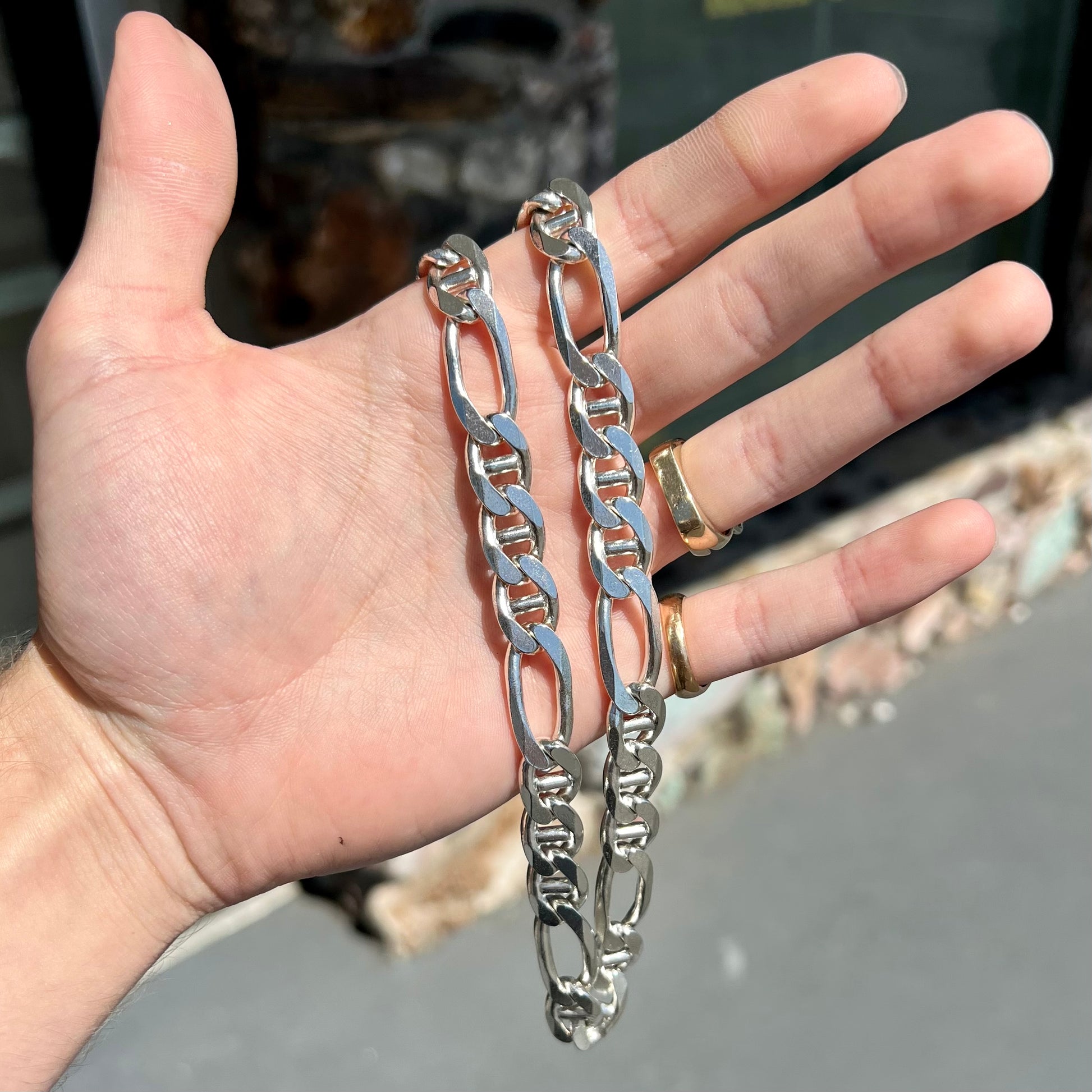 A men's sterling silver figaro anchor chain.  The chain measures 22 inches in length and the links are 11mm wide.