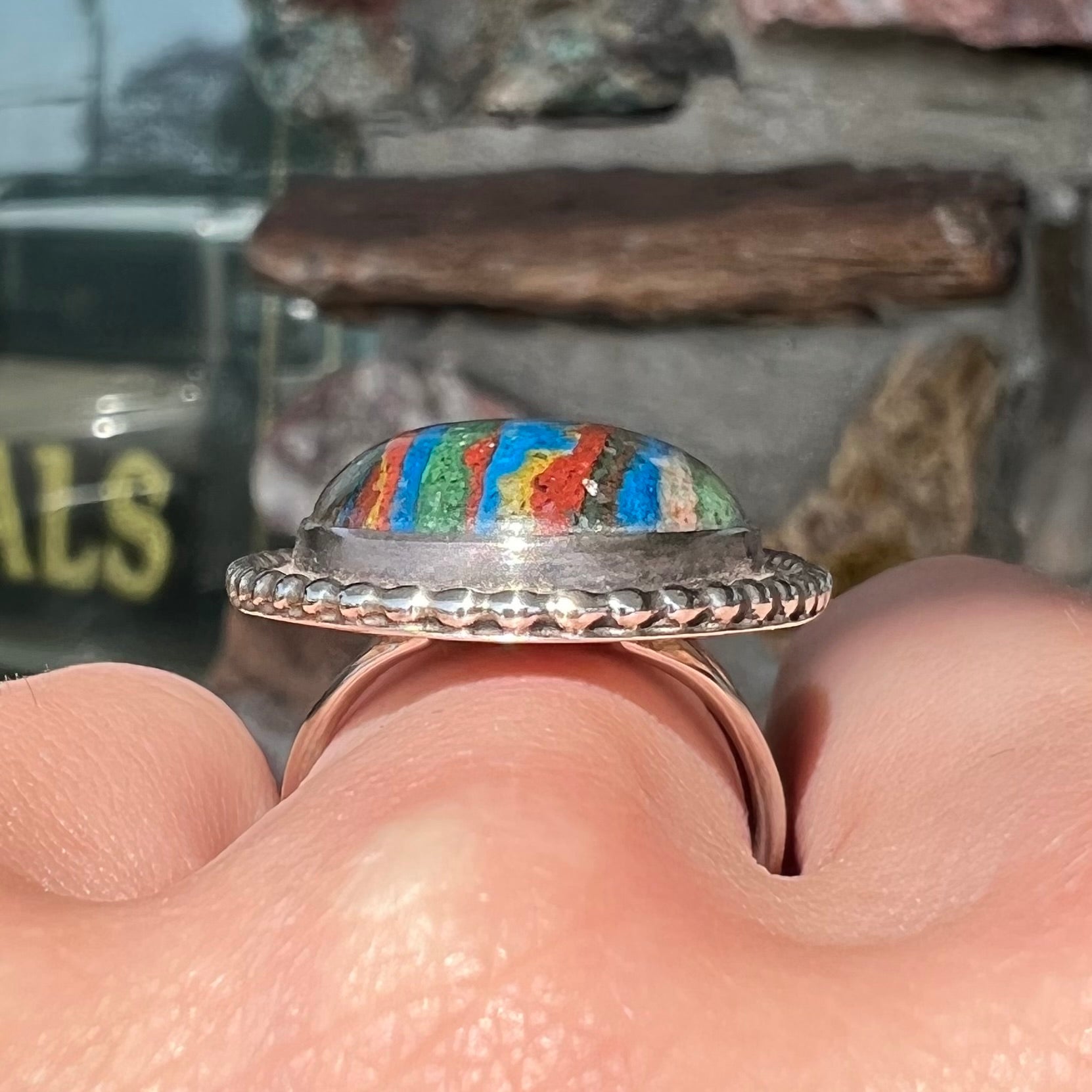 A split shank, rope bezel set silver ring set with an oval cut fordite paint stone.