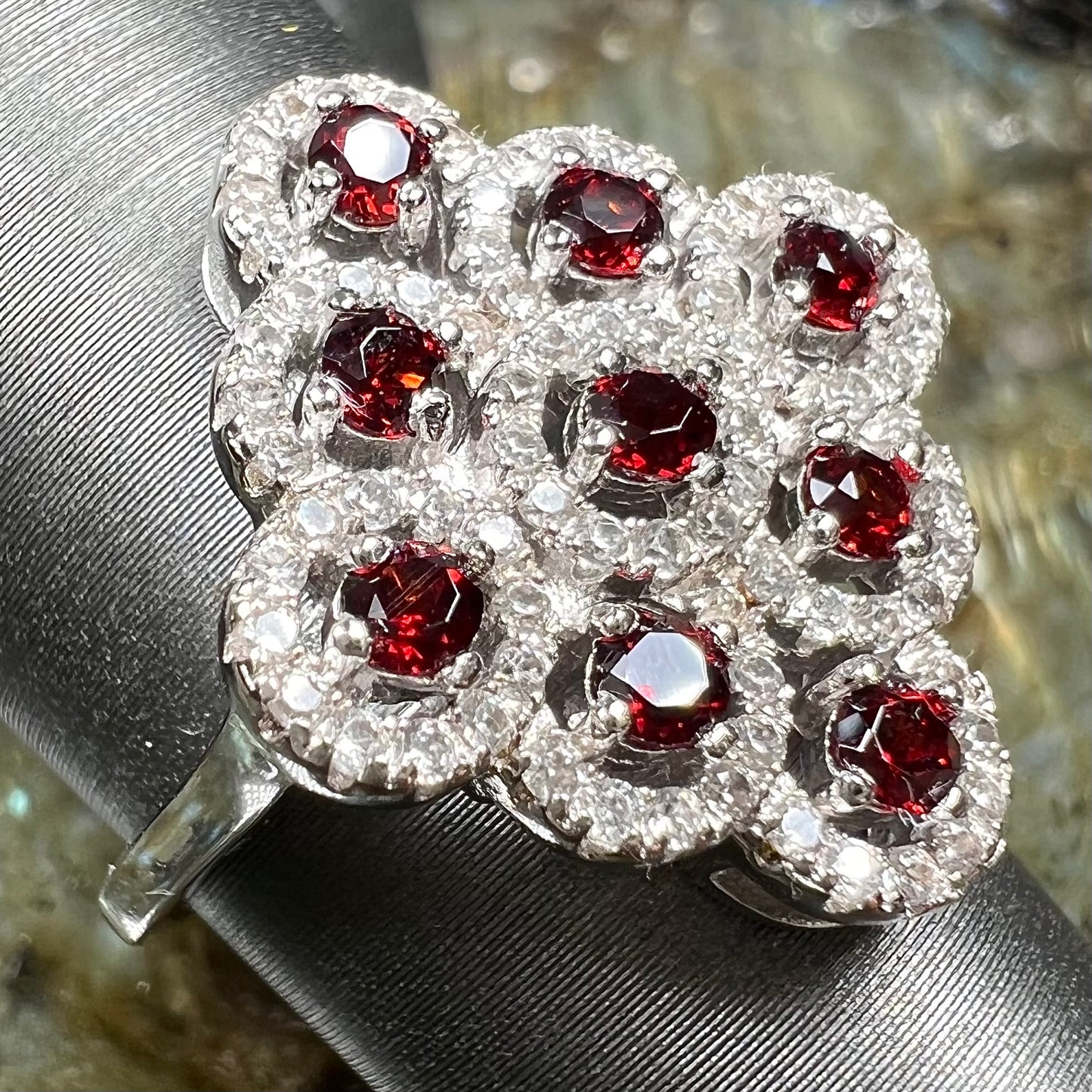 A sterling silver cluster ring set with round almandine garnet main stones and white zircon accents.