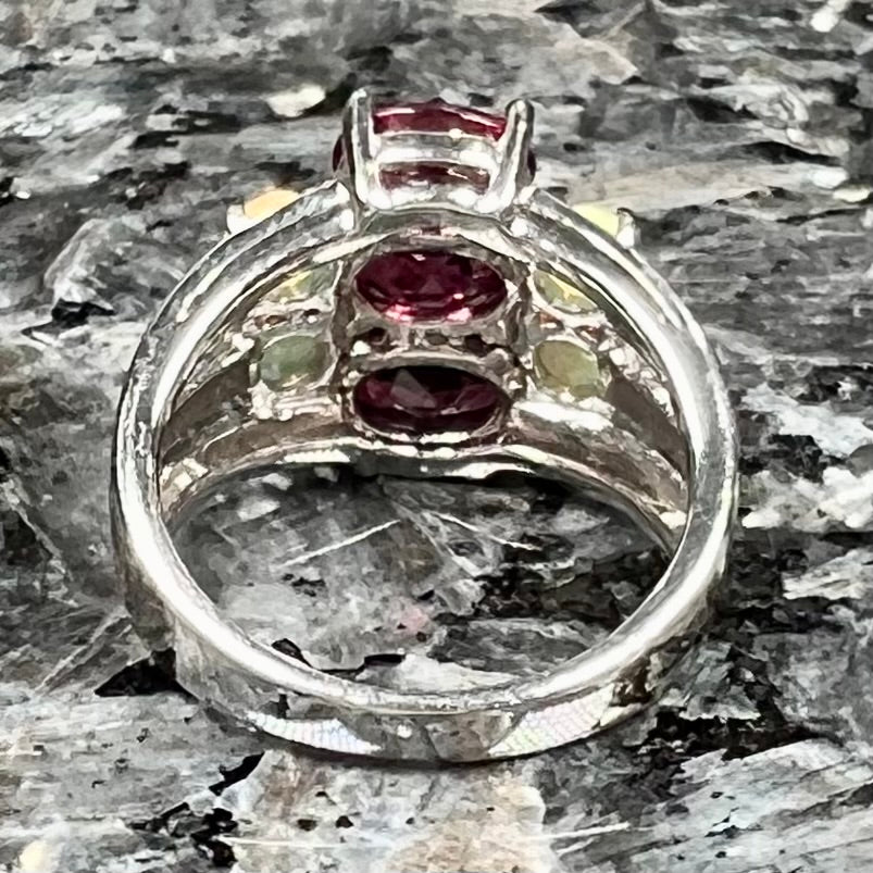 A sterling silver ring set with three oval cut rhodolite garnets and four round cabochon cut Ethiopian opals.