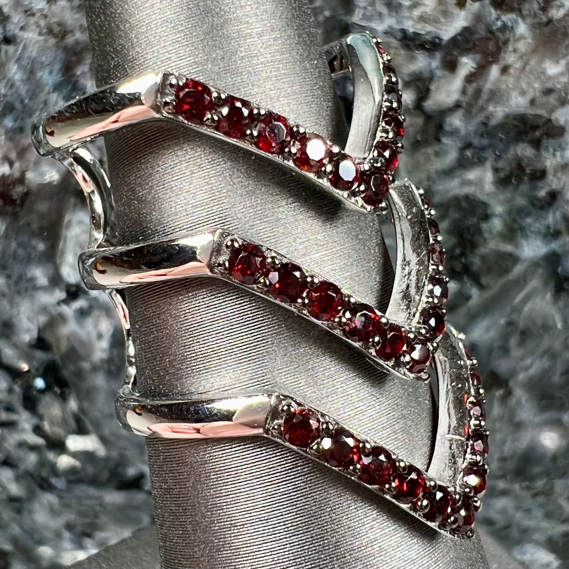 A sterling silver ring pave set with round almandine garnet stones.  The piece appears to be three rings in one.