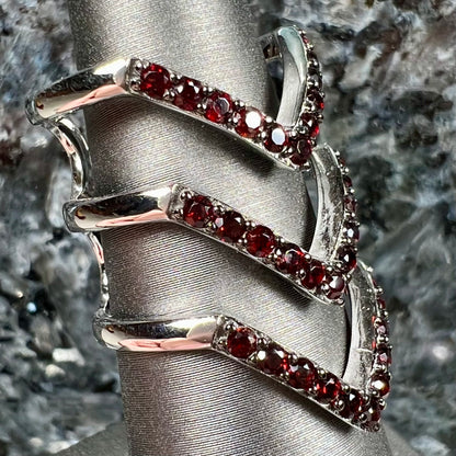 A sterling silver ring pave set with round almandine garnet stones.  The piece appears to be three rings in one.