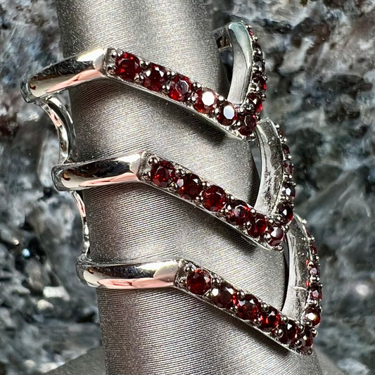 A sterling silver ring pave set with round almandine garnet stones.  The piece appears to be three rings in one.