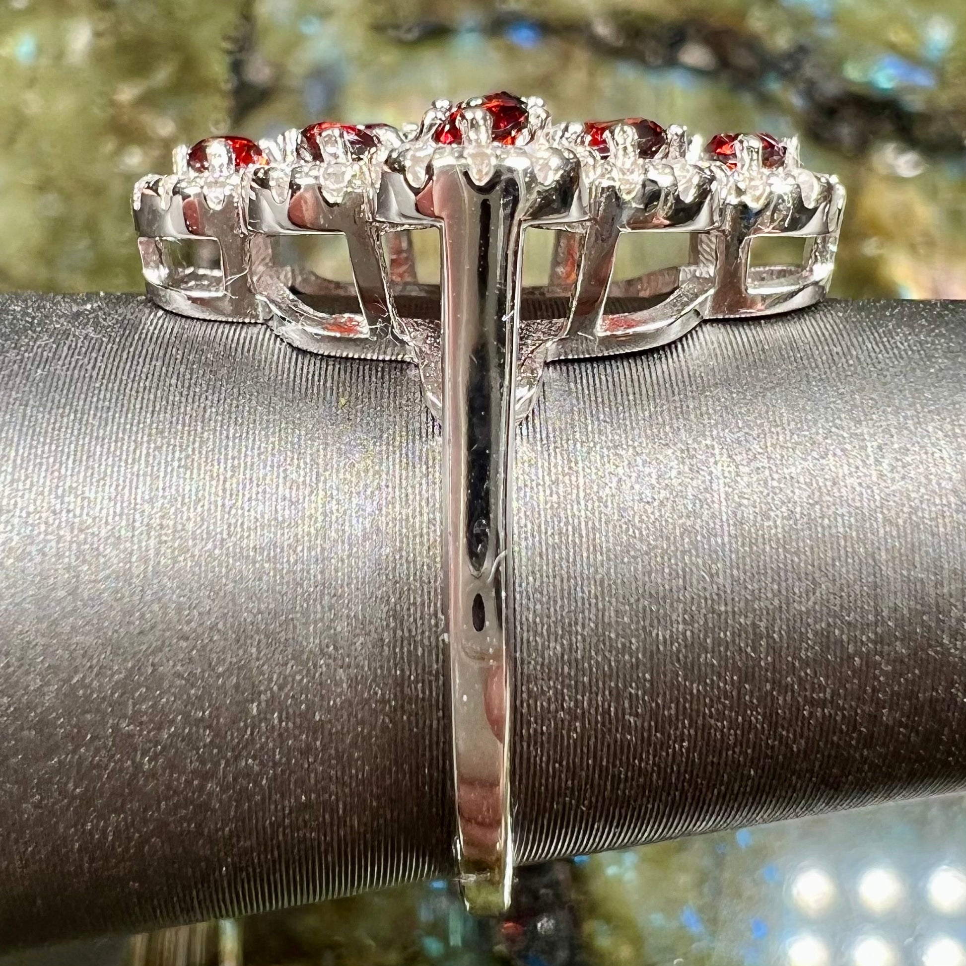 A sterling silver cluster ring set with round almandine garnet main stones and white zircon accents.