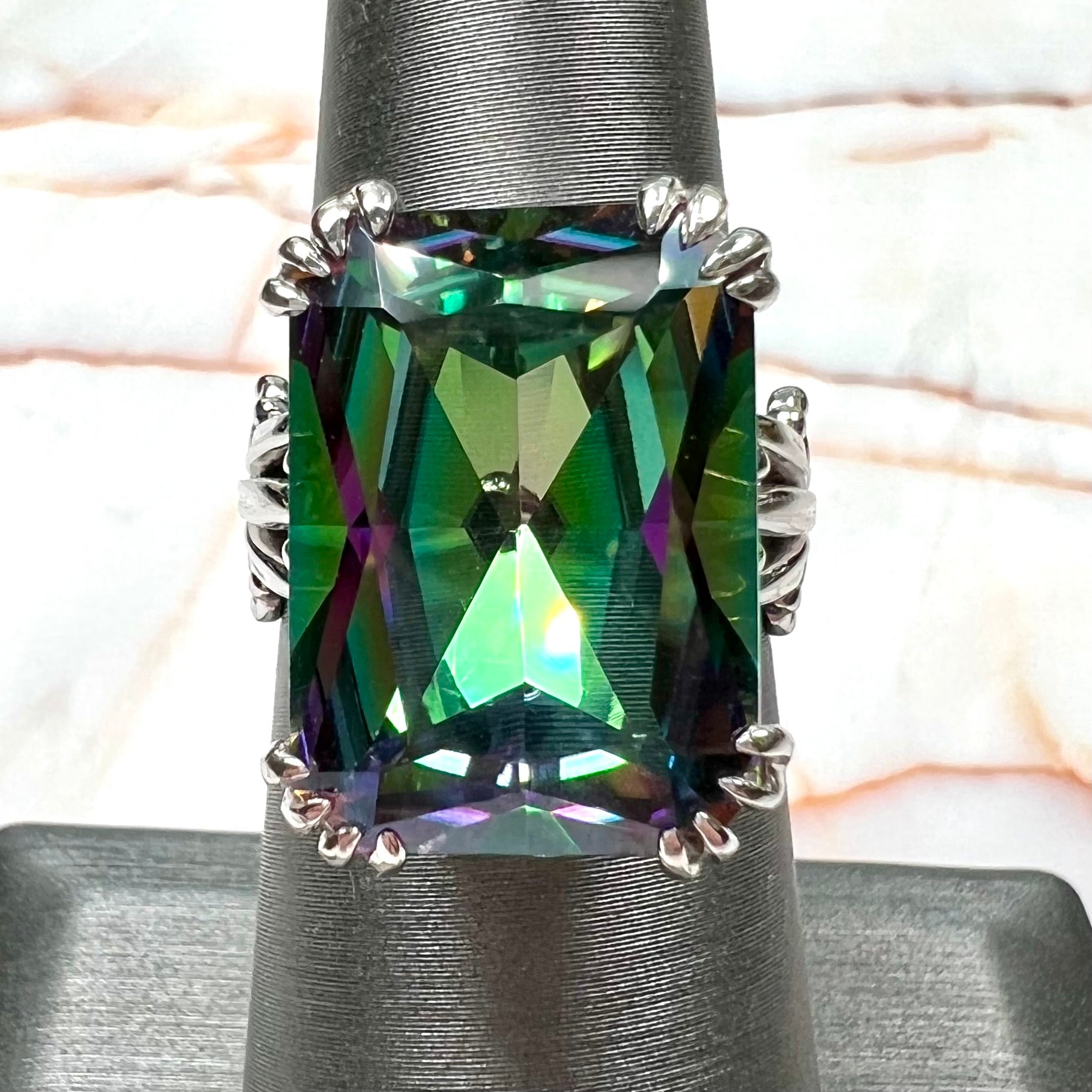 Emerald cut mystic topaz prong set in a decorative sterling silver ring.