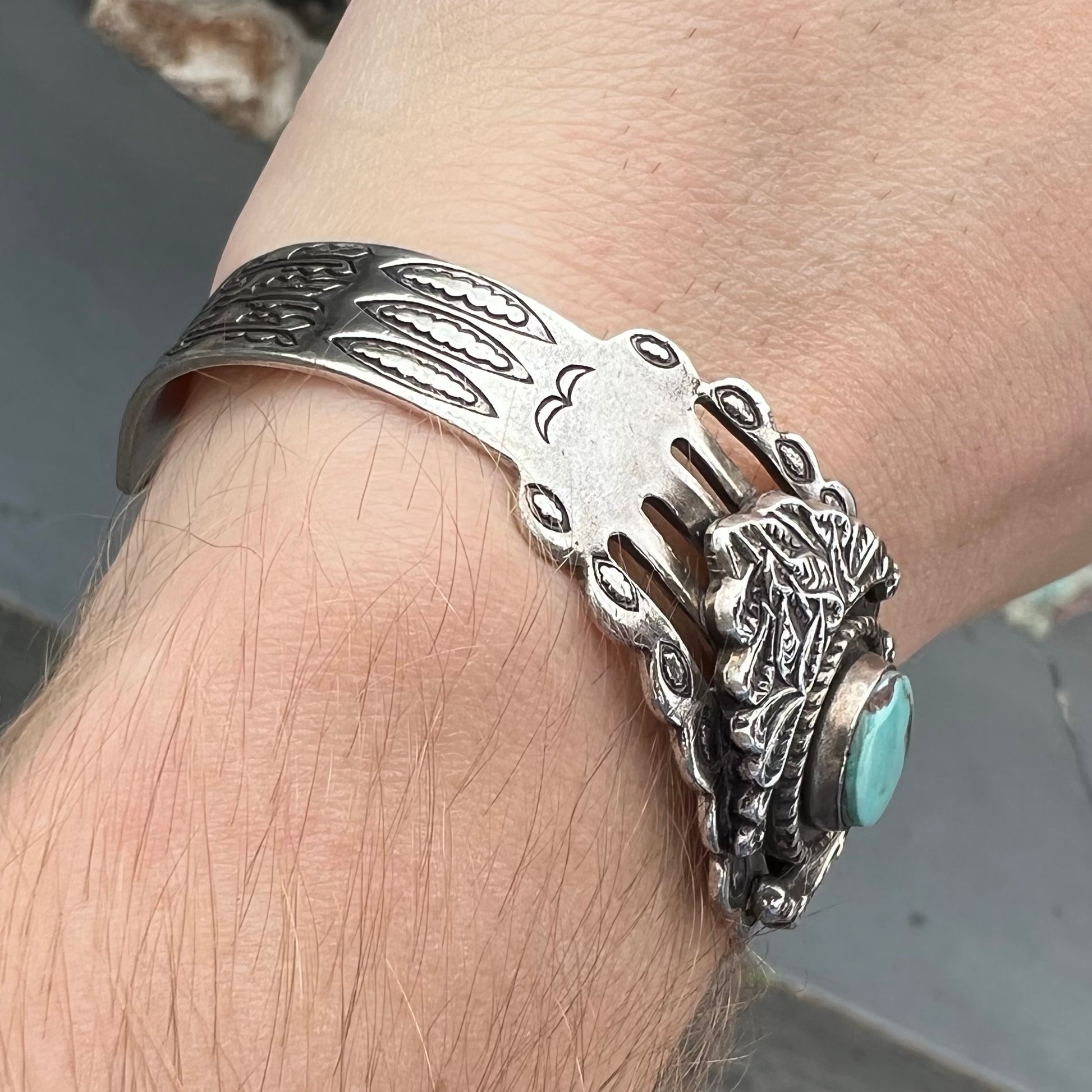 A base metal cuff bracelet set with a round cabochon cut imitation blue turquoise stone.