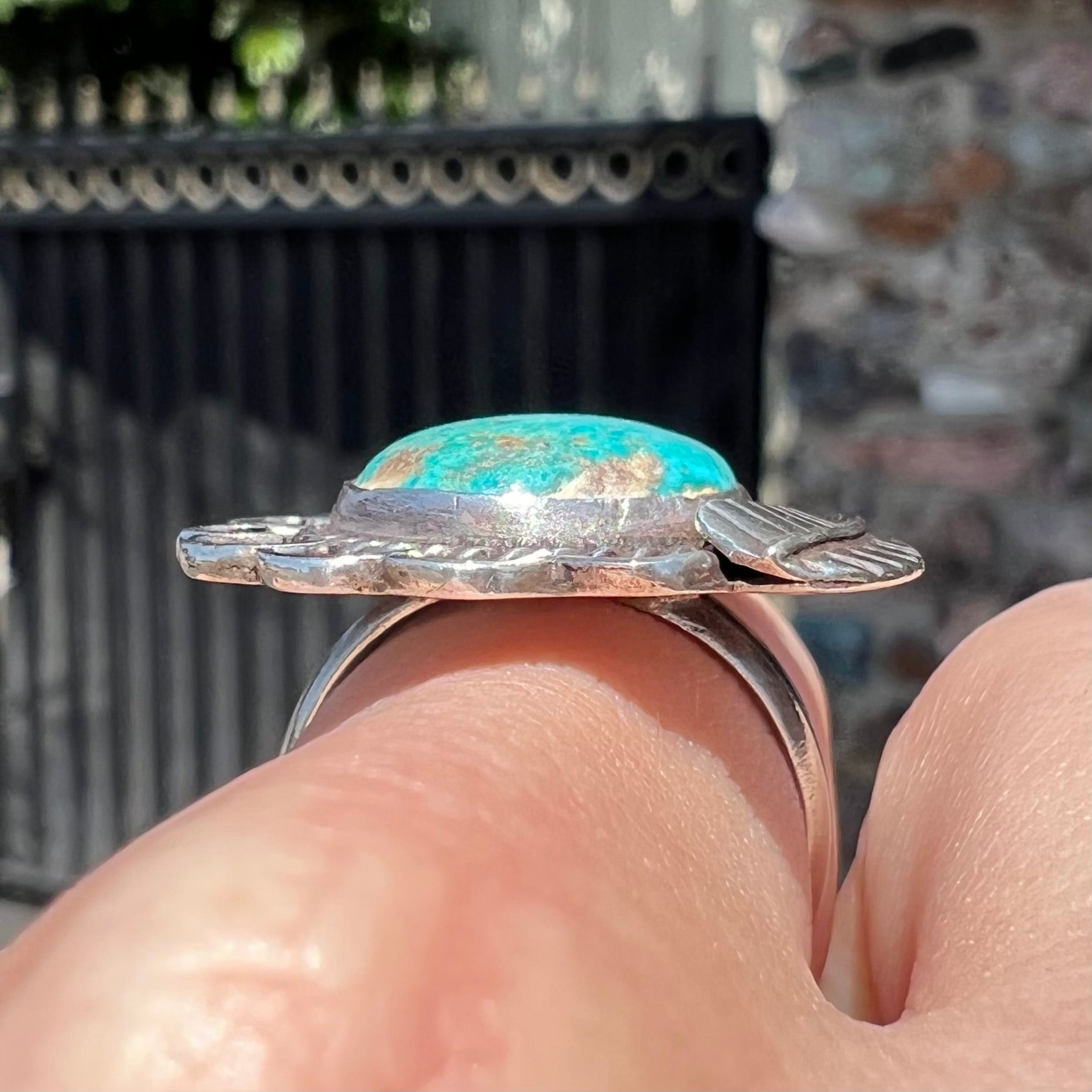 A sterling silver Navajo style ring.  The ring is set with a turquoise stone from Pilot Mountain.  There is a feather decoration next to the stone.