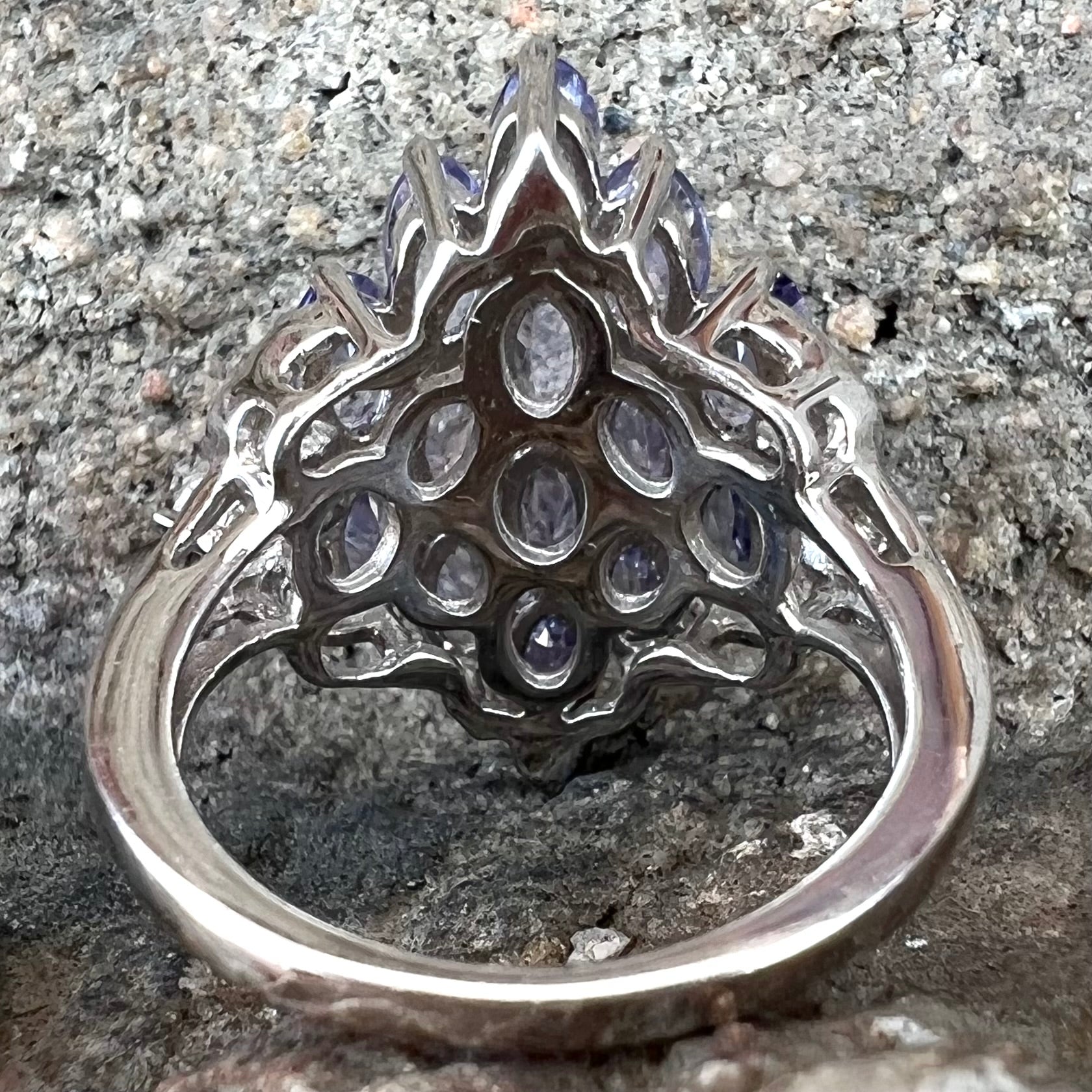 A sterling silver gemstone cluster ring set with oval cut tanzanite stones and round cubic zirconia accents.