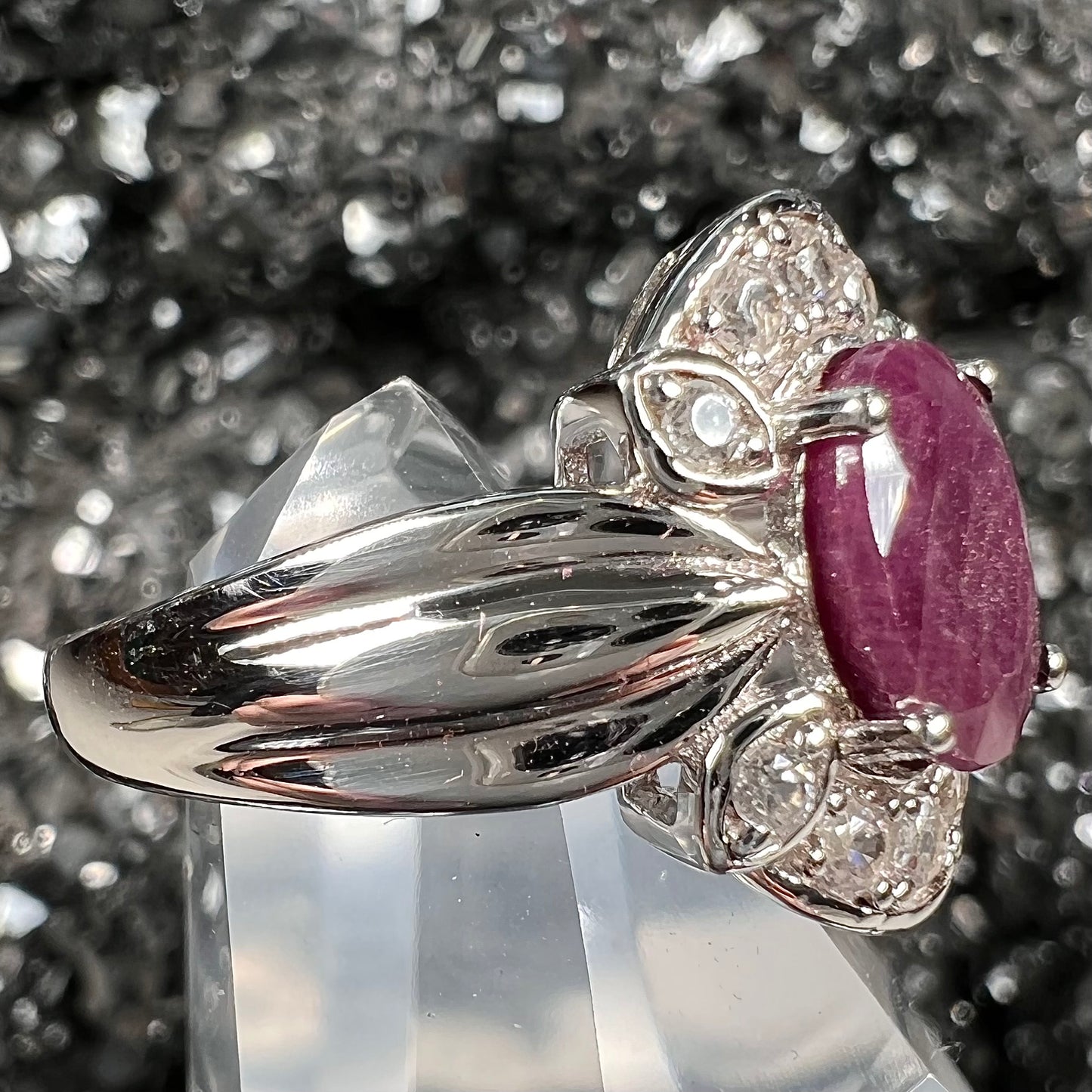 A natural, faceted oval cut ruby ring cast in sterling silver and set with cubic zirconia accents.