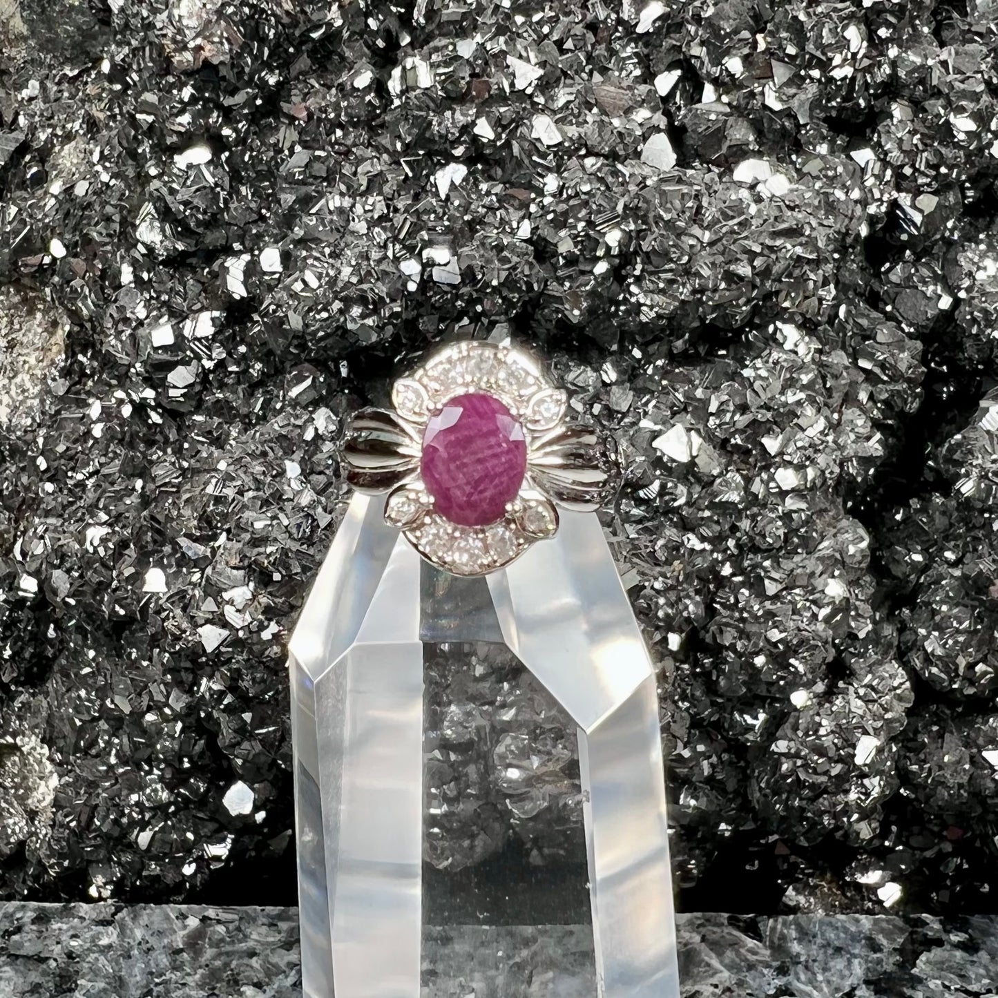 A natural, faceted oval cut ruby ring cast in sterling silver and set with cubic zirconia accents.