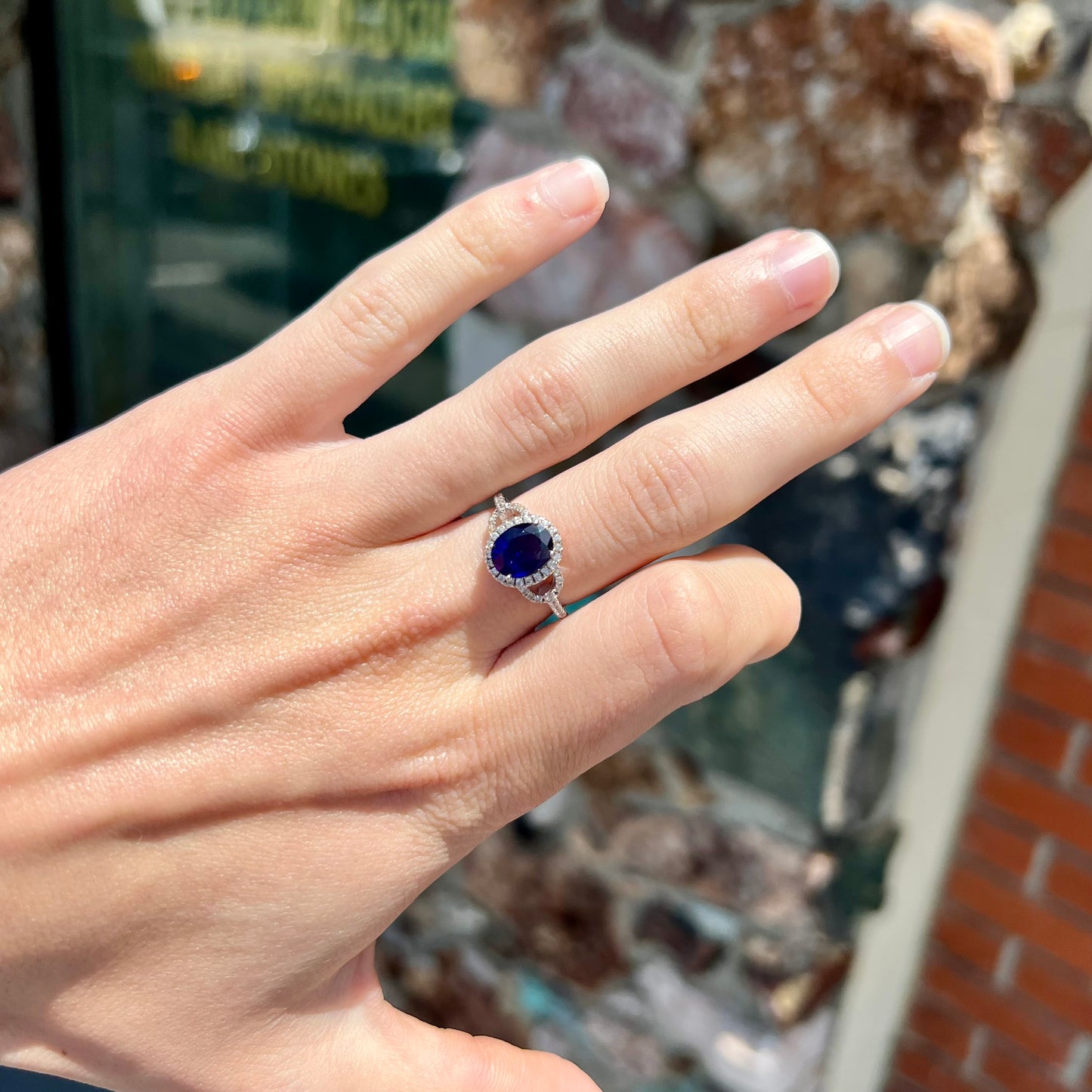 A sterling silver, white zircon halo ring set with an oval cut blue sapphire.