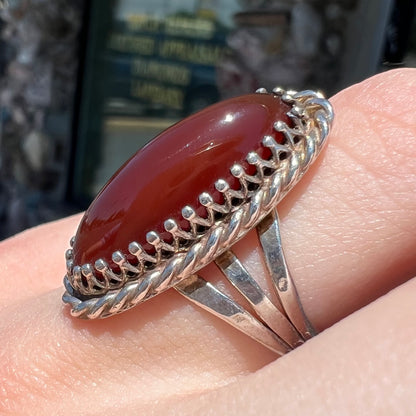 A split shank silver ring set with a brown sard stone in a rope bezel with small prongs.