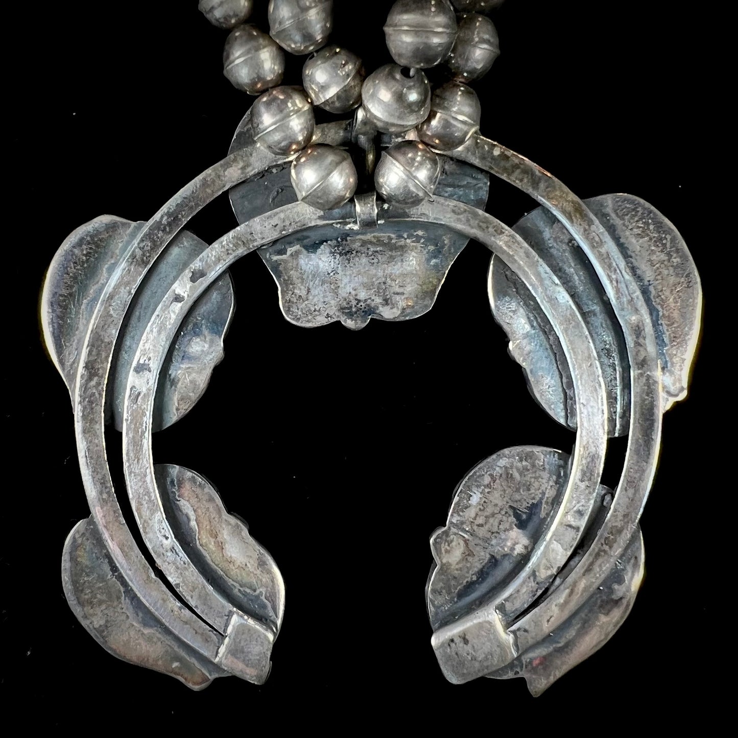 A handmade silver Navajo style squash blossom necklace set with green Kingman turquoise.
