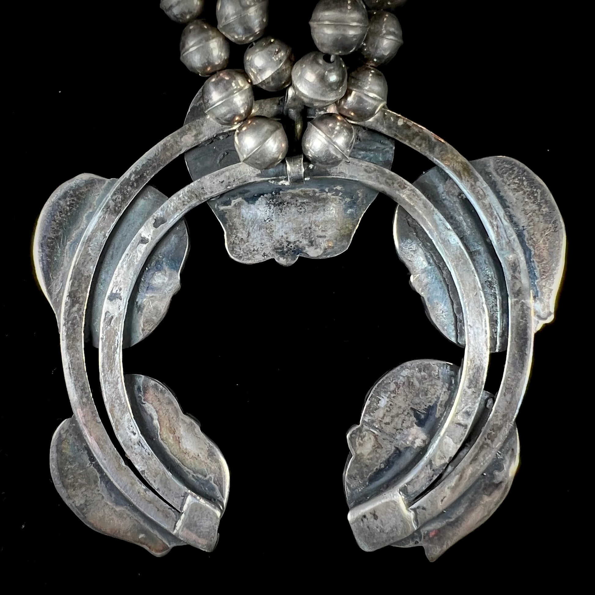 A handmade silver Navajo style squash blossom necklace set with green Kingman turquoise.