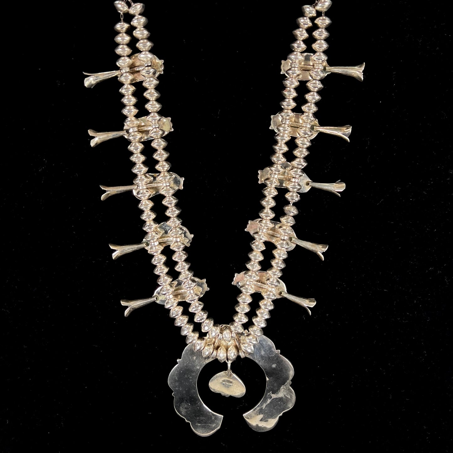 A Navajo style squash blossom necklace set with red coral branches, handmade by artist Delbert Chatter.