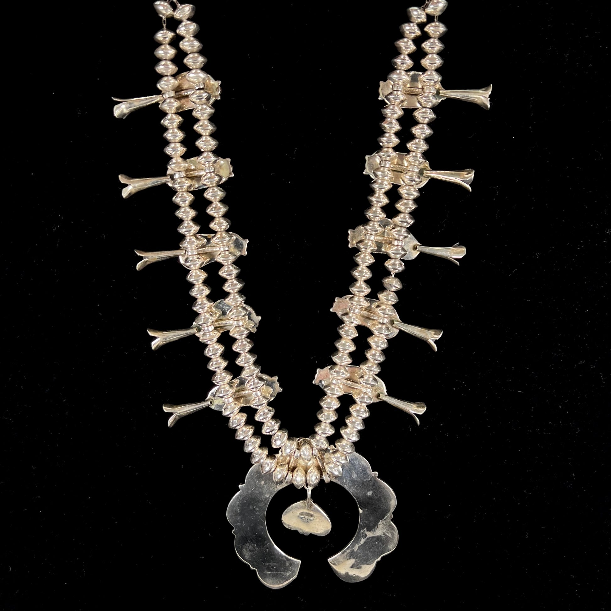 A Navajo style squash blossom necklace set with red coral branches, handmade by artist Delbert Chatter.