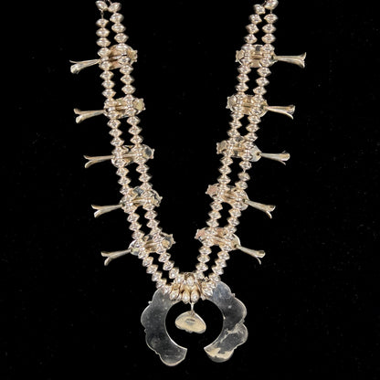 A Navajo style squash blossom necklace set with red coral branches, handmade by artist Delbert Chatter.