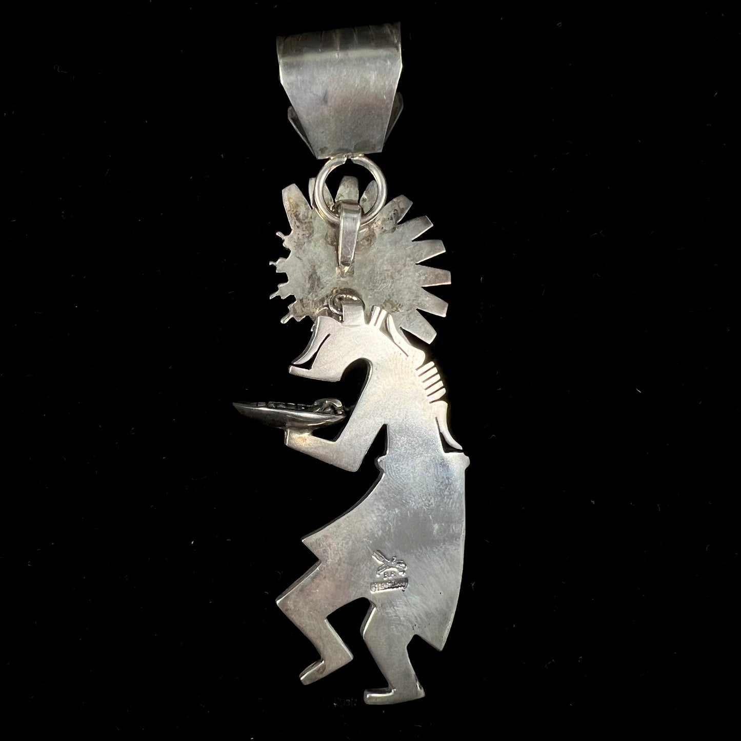 A "Navajo Sunface" kachina doll pendant made from sterling silver by artist Bennie Ration.  The piece measures four and a half inches long.