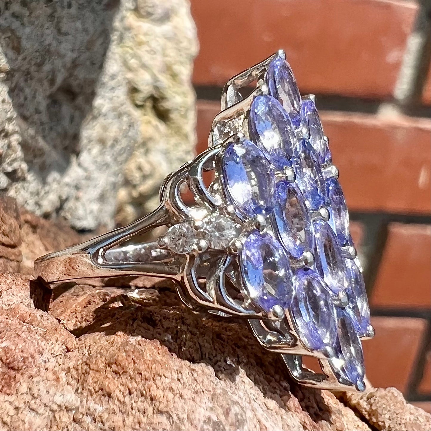 A sterling silver gemstone cluster ring set with oval cut tanzanite stones and round cubic zirconia accents.