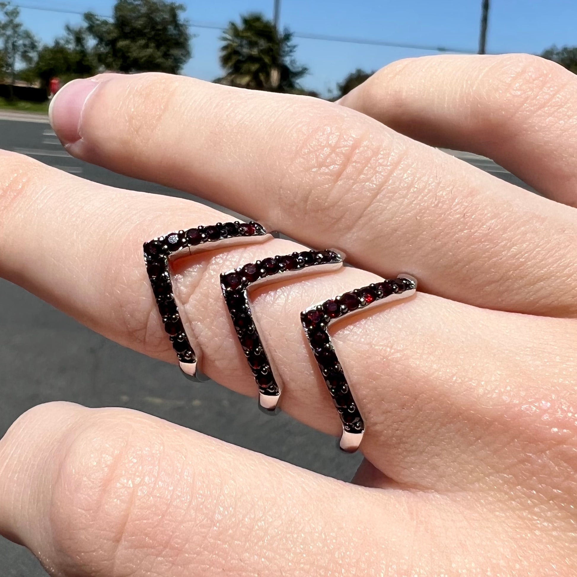 A sterling silver ring pave set with round almandine garnet stones.  The piece appears to be three rings in one.
