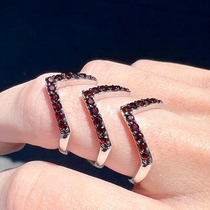A sterling silver ring pave set with round almandine garnet stones.  The piece appears to be three rings in one.