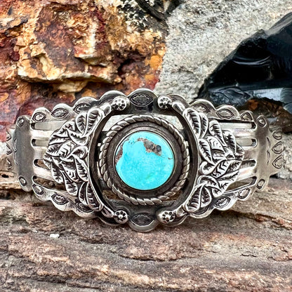 A base metal cuff bracelet set with a round cabochon cut imitation blue turquoise stone.