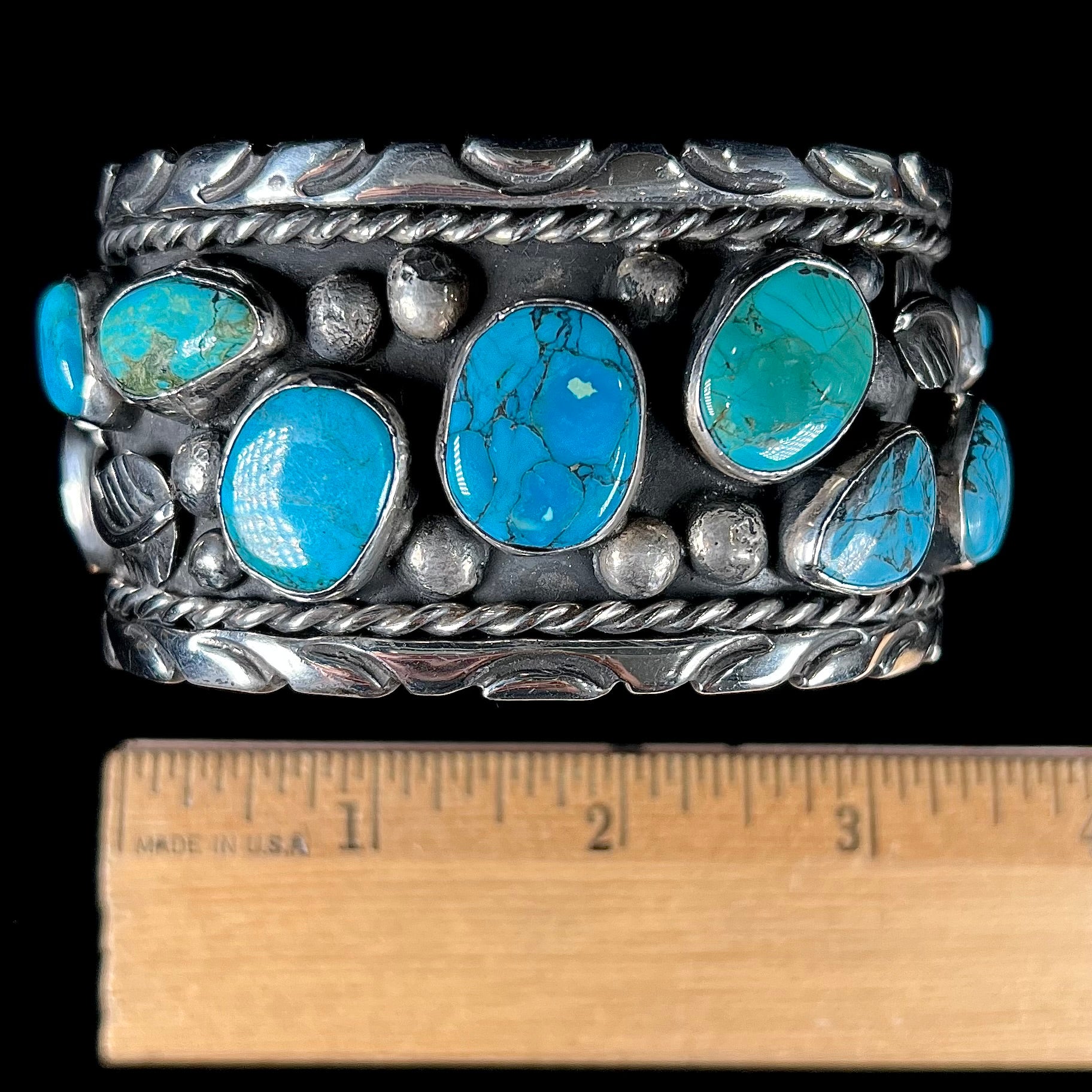 A men's sterling silver cuff bracelet bezel set with natural and synthetic turquoise stones.
