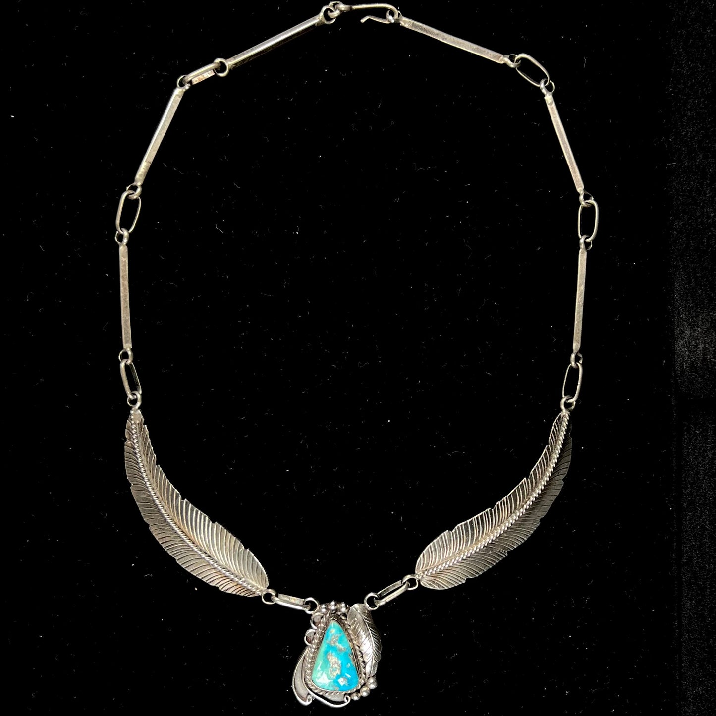 A sterling silver feather motif necklace set with a Sleeping Beauty turquoise stone, handmade by Navajo artist, Jameson Lee.