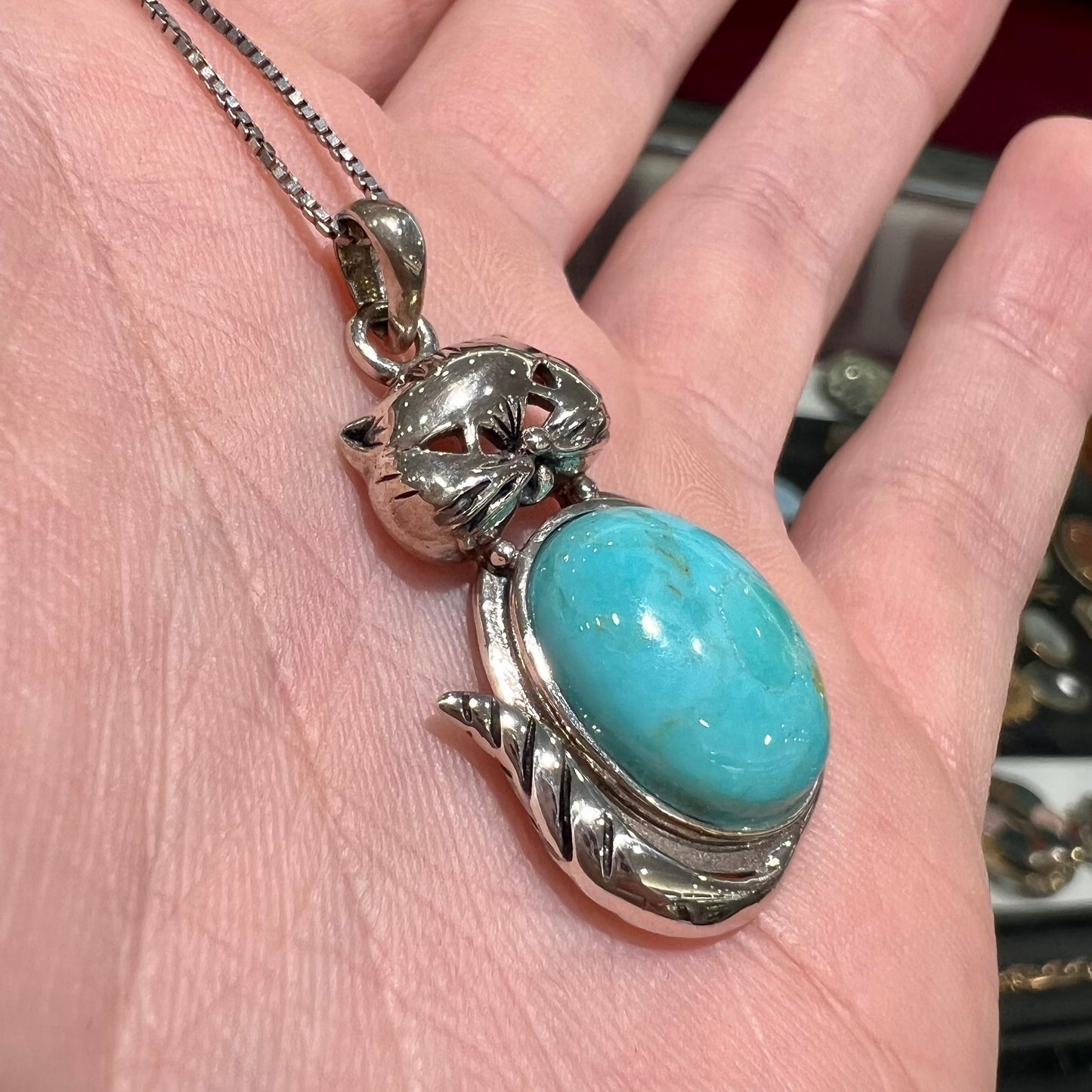 A sterling silver cat necklace set with an oval cut Sleeping Beauty turquoise stone.