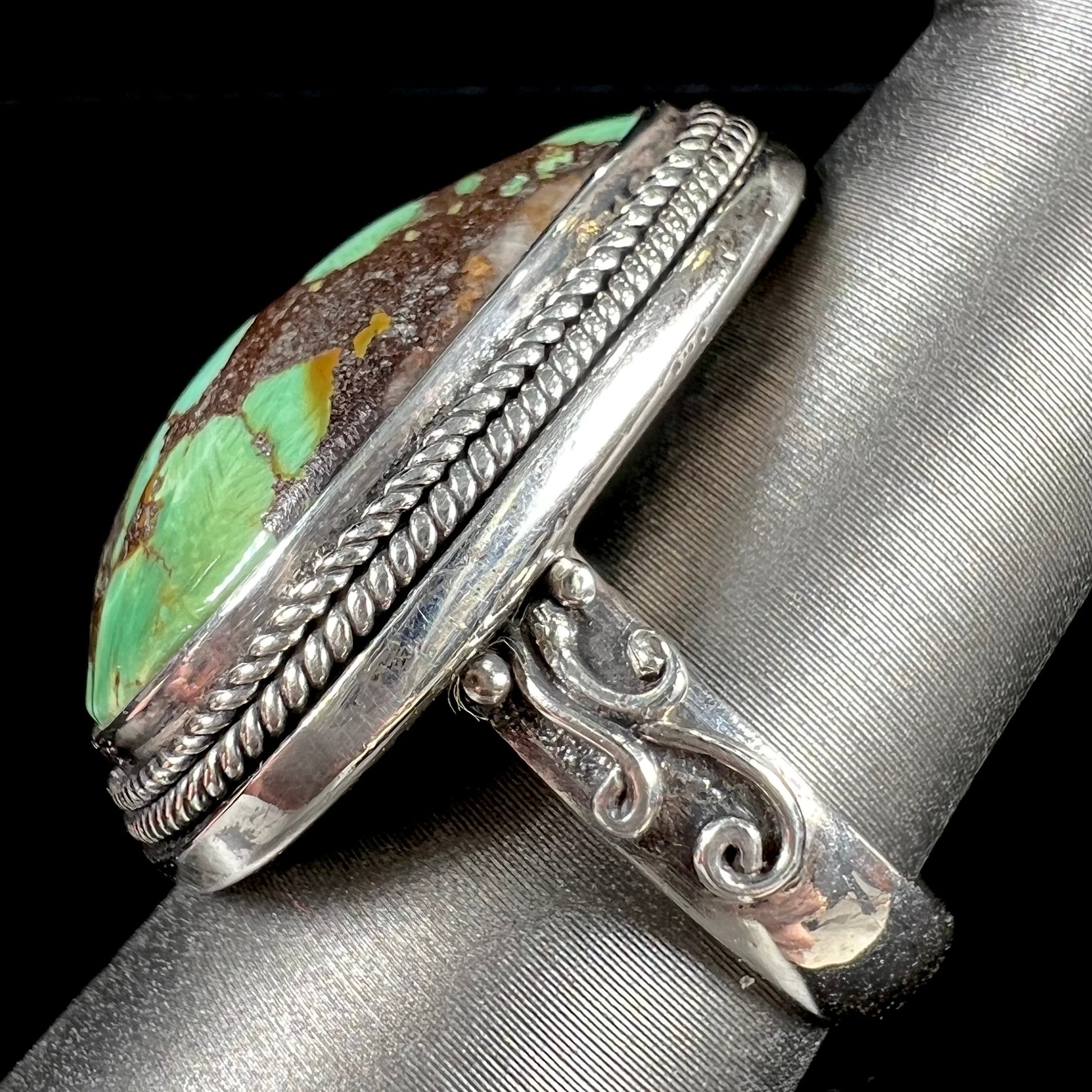 A sterling silver ring bezel set with a green spotted turquoise stone from Carico Lake, Nevada.