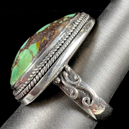 A sterling silver ring bezel set with a green spotted turquoise stone from Carico Lake, Nevada.