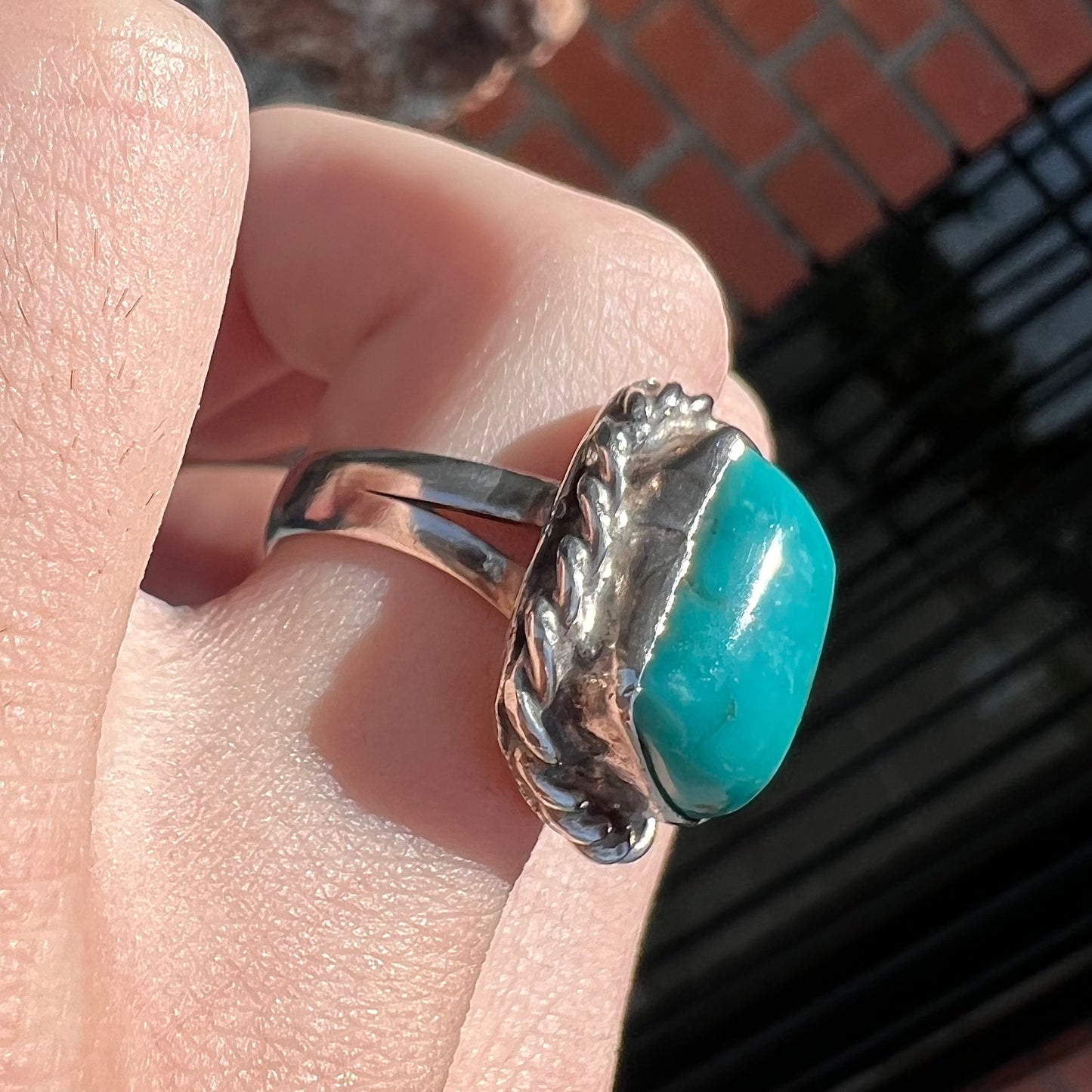 A sterling silver turquoise split shank ring.  There is a handmade silver rope around the turquoise.