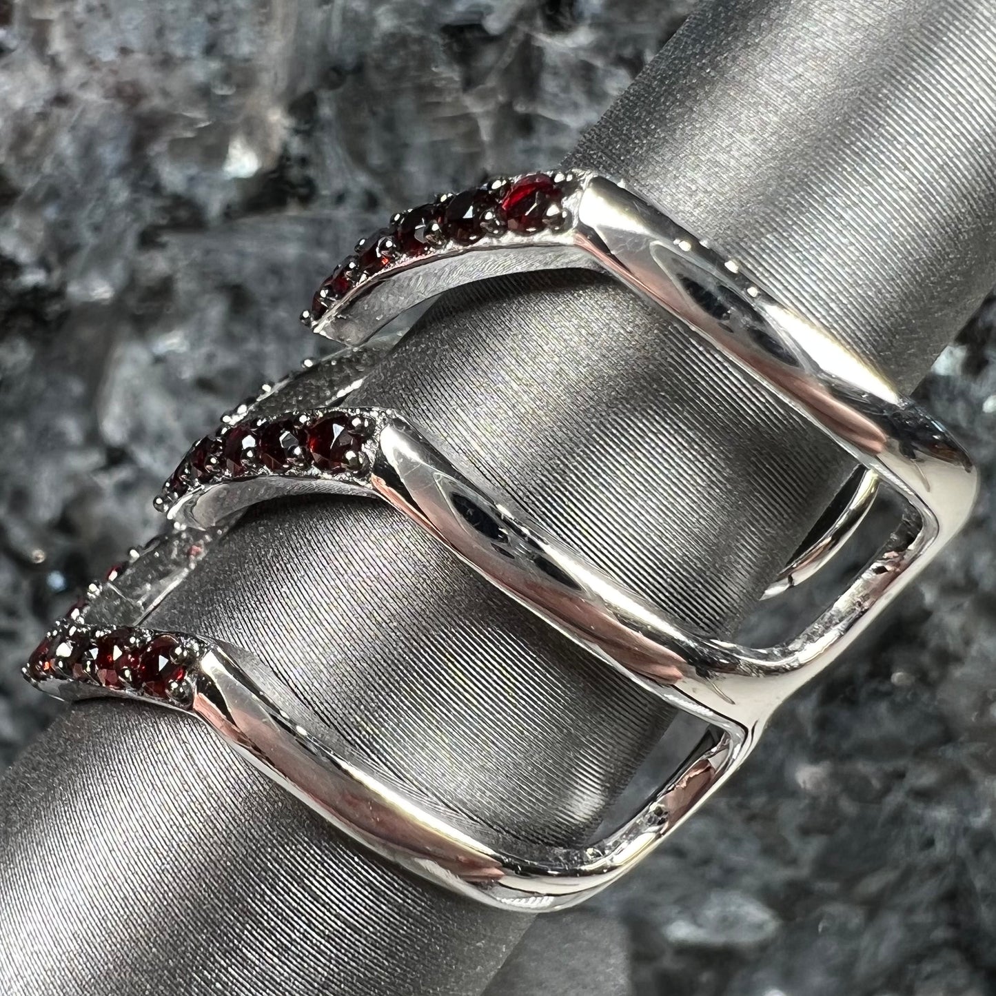 A sterling silver ring pave set with round almandine garnet stones.  The piece appears to be three rings in one.