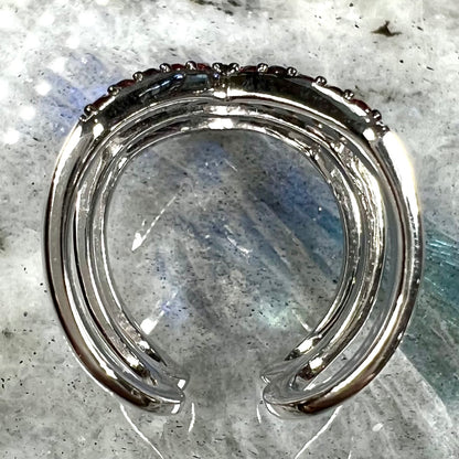 A sterling silver ring pave set with round almandine garnet stones.  The piece appears to be three rings in one.