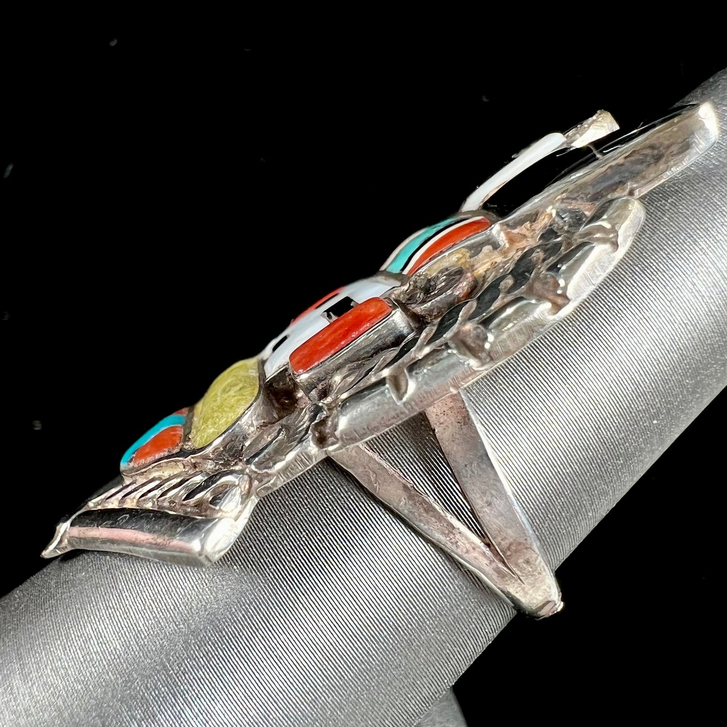 A sterling silver ring handmade in the motif of a Zuni Indian horned kachina set with onyx, turquoise, coral, mother of pearl, and sulfur quartz stones.