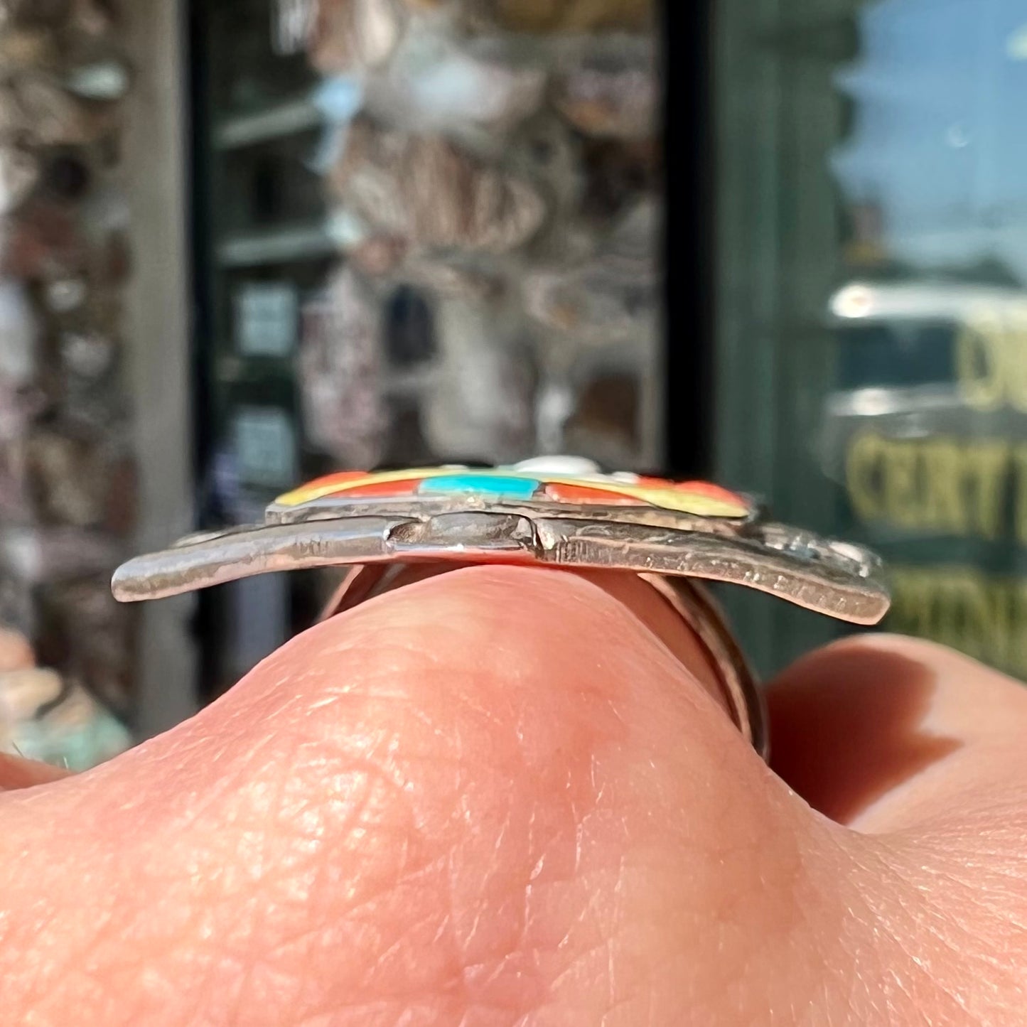 A sterling silver ring handmade in the motif of a Zuni Indian horned kachina set with onyx, turquoise, coral, mother of pearl, and sulfur quartz stones.