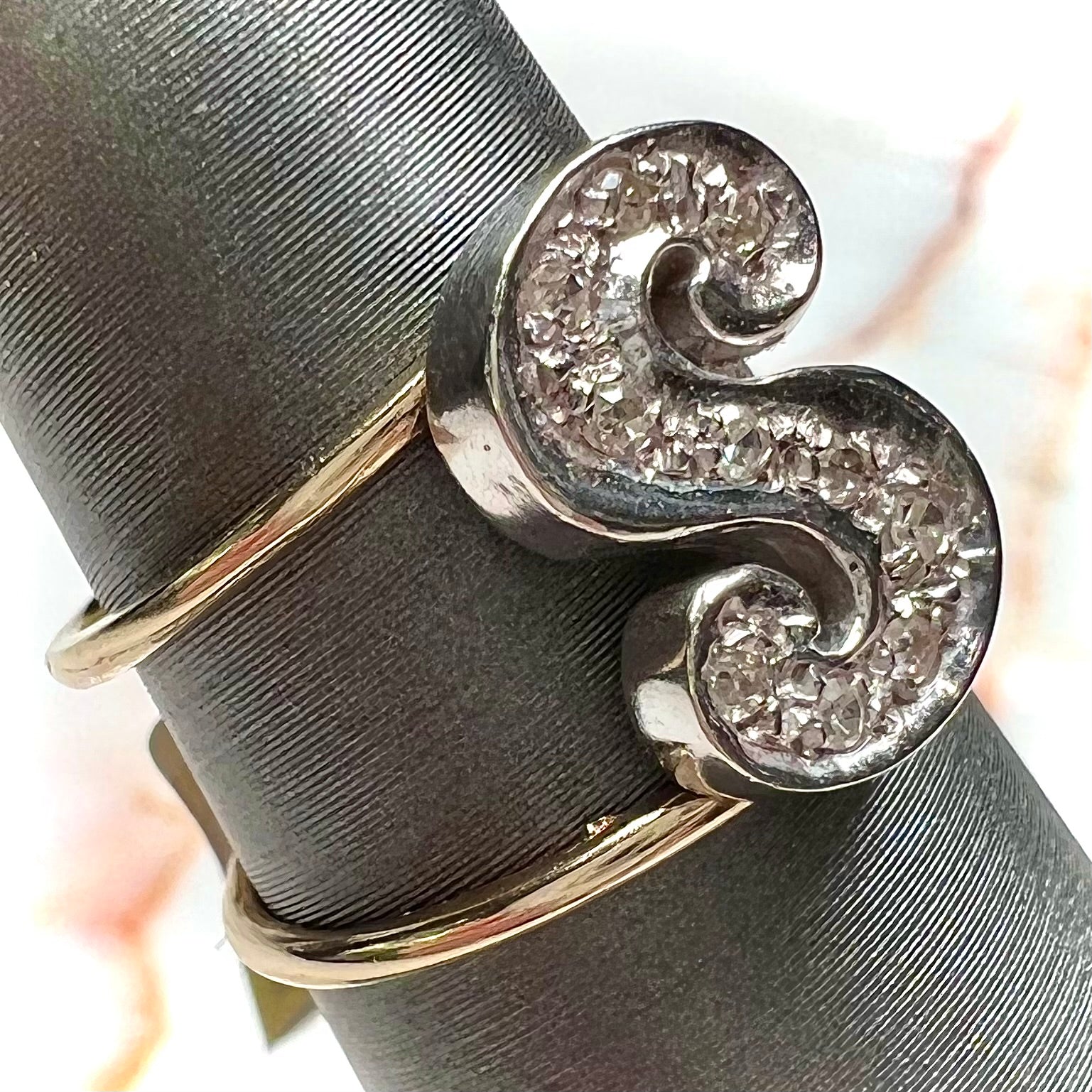 A two tone white and yellow gold initial ring of the letter "S" set with diamonds.